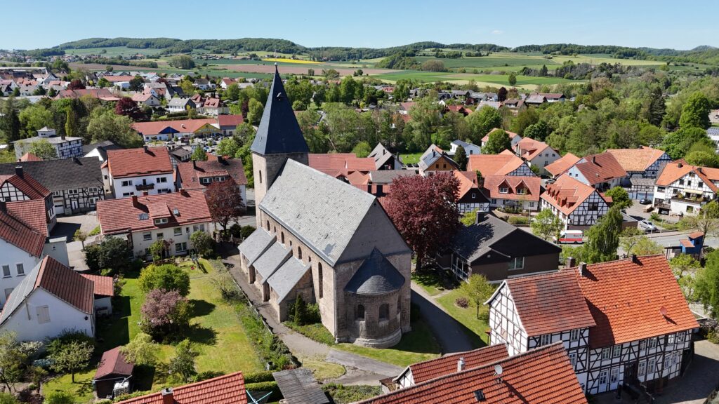 St. Johannes Kirche ind Adorf, große Kirche mit Kirchturm und Seitenschiffen umgeben von Fachwerkhäusern. 