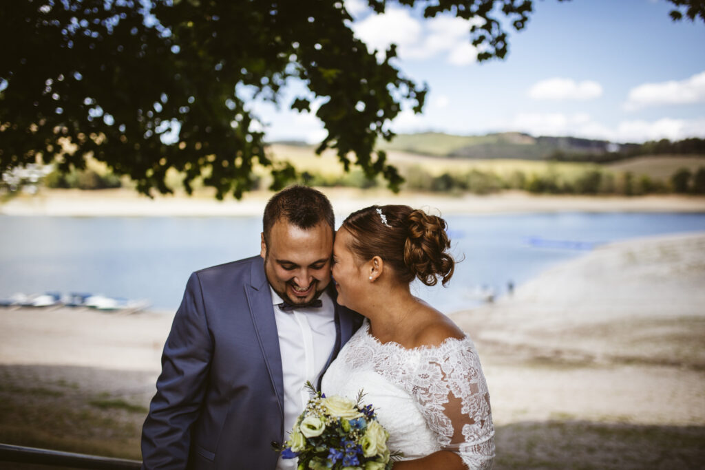 Im Vordergund ein Pärchen im Hochzeitskleidung, im Hintergrund der Diemelsee.