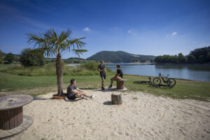 Badestrand mit Palme und Radfahrern im Hintergrund der Diemelsee.