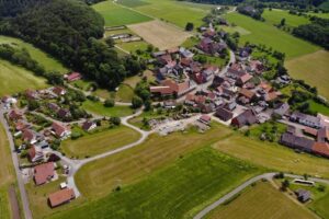 Ortsteil Schweinsbühl von oben. Einige Häuser eingebettet in grüne Wiesen und Wälder